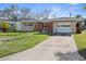 Inviting single-story home with a well-kept lawn, a paved driveway, and a convenient attached garage for easy access at 2491 Coronado Way, Dunedin, FL 34698