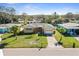 Charming single-story home featuring a well-manicured front lawn, palm trees, and an attached garage at 2491 Coronado Way, Dunedin, FL 34698