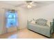 This is a bedroom with a ceiling fan and natural lighting, neutral tile floors, and a small window at 29523 Waggle Dr, San Antonio, FL 33576