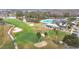 Aerial view of the golf course highlighting putting greens and a community clubhouse with pool at 29523 Waggle Dr, San Antonio, FL 33576