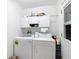 This laundry room features a washer, dryer, cabinets, and a white door with a window pane at 29523 Waggle Dr, San Antonio, FL 33576