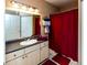 Bathroom featuring large mirror, shower with red curtain and neutral colored cabinets at 3673 Kings Rd # 102, Palm Harbor, FL 34685