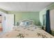 Bedroom with green walls, bamboo-themed bedding, white wicker furniture, and bright light at 37150 Sandra Ave, Zephyrhills, FL 33542
