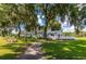 Clubhouse exterior surrounded by trees, a sidewalk, and lawn, offering a picturesque setting for community activities at 37150 Sandra Ave, Zephyrhills, FL 33542