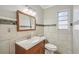 Bathroom with tiled walls, a wooden-framed mirror, a window, and a vanity with counter-space at 4101 W Leila Ave, Tampa, FL 33616