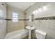 Tiled bathroom with a shower-tub combination and a pedestal sink offers a clean and functional space at 4101 W Leila Ave, Tampa, FL 33616