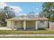 Charming home featuring a covered front porch, green lawn, and mature trees at 4101 W Leila Ave, Tampa, FL 33616