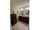 This bathroom has double sinks, granite counters, decorative mirrors, and a decorative storage cabinet at 4915 Pond Ridge Dr, Riverview, FL 33578