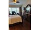 This bedroom has a view outside the large windows, a television and work area, and dark wood flooring at 4915 Pond Ridge Dr, Riverview, FL 33578