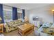 Inviting living room with large windows, blue drapes, and tropical themed furniture at 5840 30Th S Ave # 208, Gulfport, FL 33707