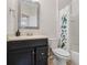 Bathroom features a vanity with granite countertop, framed mirror, toilet and shower with patterned curtain at 8835 Moonlit Meadows Loop, Riverview, FL 33578
