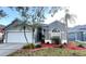 Charming single-story home with a manicured lawn, landscaped flowerbeds, and attached two-car garage at 10251 Oasis Palm Dr, Tampa, FL 33615