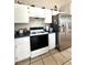 Kitchen featuring white cabinets, stainless steel refrigerator and a black top stove with tile flooring at 10251 Oasis Palm Dr, Tampa, FL 33615