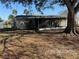 View of the backyard of the house with a screen enclosed patio, shade tree, and tropical palm trees in view at 11470 88Th Ter, Seminole, FL 33772