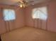 A cozy bedroom featuring two windows and a ceiling fan with lighting at 11470 88Th Ter, Seminole, FL 33772