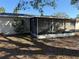 View of the exterior of the screen enclosed patio, with seating, attached to the house with a lush tree at 11470 88Th Ter, Seminole, FL 33772