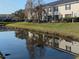 Peaceful backyard view of waterfront property with lush green grass and reflection of the building on the lake at 12287 Country White Cir, Tampa, FL 33635