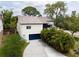 Stunning home exterior featuring a blue garage door, complemented by lush tropical landscaping and a well-maintained driveway at 2003 Mcmullen Ave, Dunedin, FL 34698