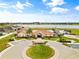 Community clubhouse with a pool, surrounded by a circular driveway, manicured lawns, and a serene lake view at 2604 Dakota Rock Dr, Ruskin, FL 33570
