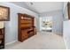 Cozy living room with plush carpeting, a wooden hutch, and sliding glass doors to the pool area at 3414 Shady Brook Ln, Sarasota, FL 34243