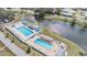 Aerial view of a community pool area with two large pools, lounge chairs, and a nearby waterway at 36645 Kay Ave, Zephyrhills, FL 33542