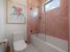 Charming bathroom with unique pink tile, a modern tub-shower, and whimsical artwork above toilet at 4110 W Swann Ave, Tampa, FL 33609