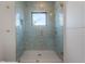 The shower has light blue tiles and modern fixtures, a built-in shelf, and glass door at 4110 W Swann Ave, Tampa, FL 33609