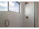 Modern shower featuring white tiling, glass door, and window providing natural light at 4110 W Swann Ave, Tampa, FL 33609