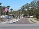 Community entrance with landscaped median, palm trees, and an American flag on a clear day at 4845 Baker Ave, Zephyrhills, FL 33541