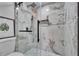 Close up on marble shower with glass door and black hardware in remodeled bathroom at 5602 Bay Blvd, Port Richey, FL 34668