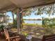 View from a screened-in back porch with chairs overlooking a serene lake and landscaped yard at 6910 Lake Place Ct, Tampa, FL 33634