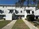 View of the townhouse with a lawn area and sidewalks leading to the front doors with the building number on the exterior wall at 7129 E Bank Dr # 7129, Tampa, FL 33617