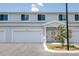 New townhouse exterior featuring a one-car garage, white trim, and a blooming decorative tree at 7529 62Nd N Way, Pinellas Park, FL 33781