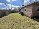 Exterior back of home with wood fence, AC unit and green lawn under blue skies at 7563 Meadowlawn N Dr, St Petersburg, FL 33702