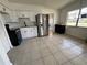 Eat-in kitchen boasts stainless steel refrigerator, white cabinets, and modern light fixtures at 7563 Meadowlawn N Dr, St Petersburg, FL 33702