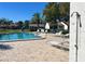 Community pool surrounded by lounge chairs with a clear blue sky above the complex at 7623 Radcliffe Cir # 211A, Port Richey, FL 34668