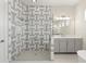 Bathroom featuring a glass enclosed shower with decorative gray and white tiling next to a sink and vanity at 8977 Players Dr, Brooksville, FL 34613