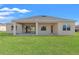 Rear exterior view of the home featuring a covered patio and a well-maintained lawn at 8977 Players Dr, Brooksville, FL 34613