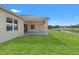 Rear exterior view of the home showcasing a covered patio overlooking the grassy lawn and golf course at 8977 Players Dr, Brooksville, FL 34613