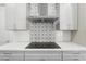 Modern kitchen featuring white cabinets, quartz countertops, decorative backsplash, and a sleek induction cooktop at 8977 Players Dr, Brooksville, FL 34613