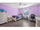 Charming bedroom featuring purple walls, wood-look floors, and a view of the neighborhood at 1240 Ridgegrove S Dr, Palm Harbor, FL 34683