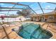 Sparkling screened-in pool featuring a connected spa and ample seating, perfect for relaxation at 1240 Ridgegrove S Dr, Palm Harbor, FL 34683