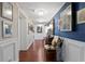 Hallway with hardwood floors, white wainscoting, and a blue accent wall adorned with art at 3301 Bayshore Blvd # 1908B, Tampa, FL 33629