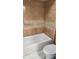 Tiled bathtub and toilet in a bathroom featuring a beige, brown, and white color scheme at 5507 Riddle Rd, Holiday, FL 34690