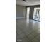 Open-concept living area with neutral tones, tile floors, and access to an enclosed patio at 5507 Riddle Rd, Holiday, FL 34690