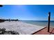 Expansive beach view with tranquil turquoise waters, pristine white sand, and inviting seating for relaxation by the sea at 611 Destiny Dr # 604, Ruskin, FL 33570