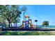 Bright playground with slides and swings set against a backdrop of sparkling waterfront and clear blue sky at 611 Destiny Dr # 604, Ruskin, FL 33570