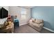 Playful bedroom with a light blue accent wall, a cozy loveseat, and shelving unit filled with toys at 7673 Yale Harbor Dr, Wesley Chapel, FL 33545