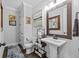 Elegant powder bath with a pedestal sink, decorative mirror and lighting, and decorative wall art at 7721 Roma Dune Dr, Wesley Chapel, FL 33545