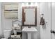 Stylish powder bath featuring a pedestal sink with granite countertop, artwork, and decorative shelving at 7721 Roma Dune Dr, Wesley Chapel, FL 33545